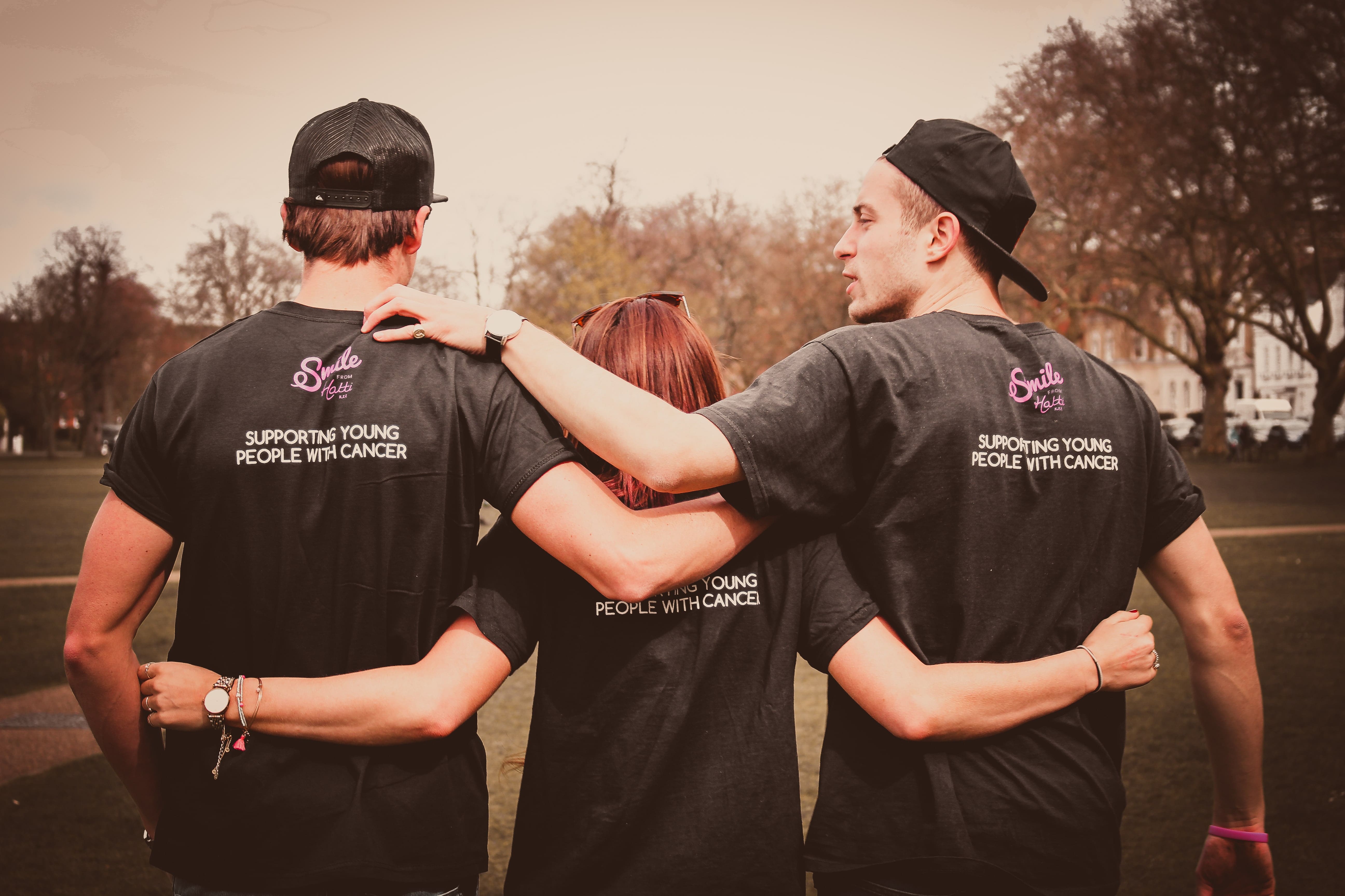 3 smile from hatti volunteers looking into the sunset, with their arms around each other